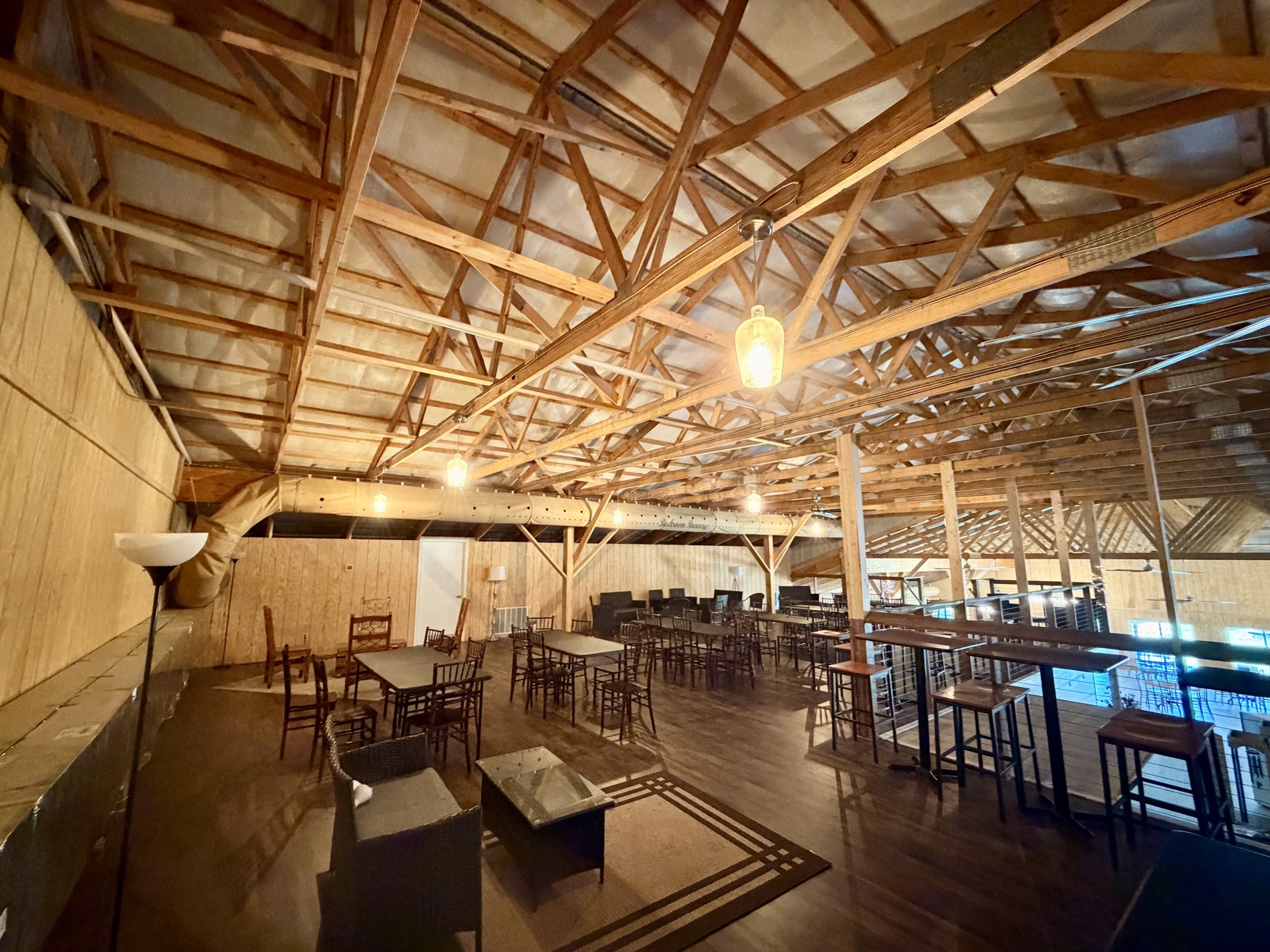 The Mezzanine overlooking the barn floor — high-top tables and dining seating along the rail