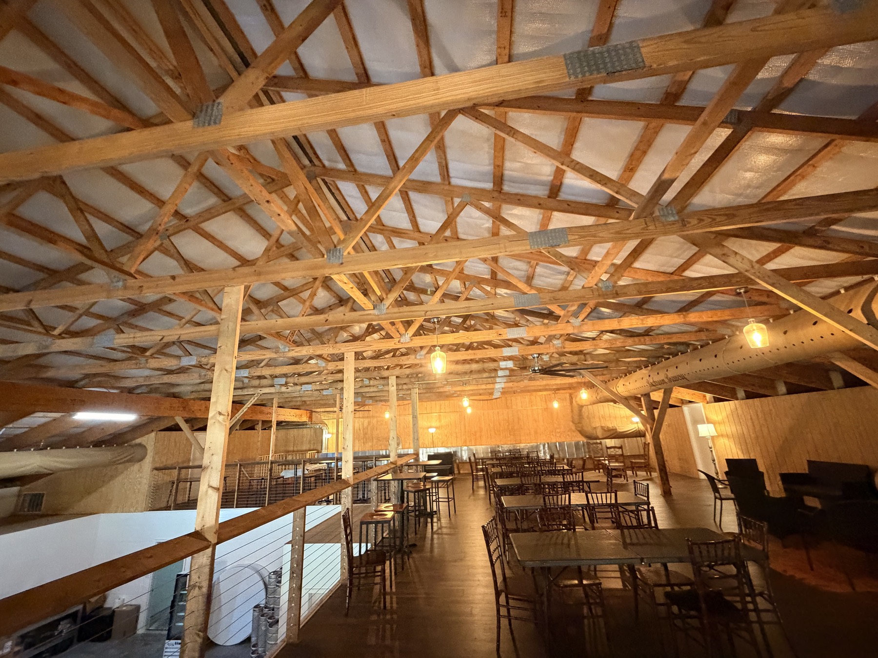 The Mezzanine lounge — sofa sets and table seating under exposed timber trusses and warm pendant lighting