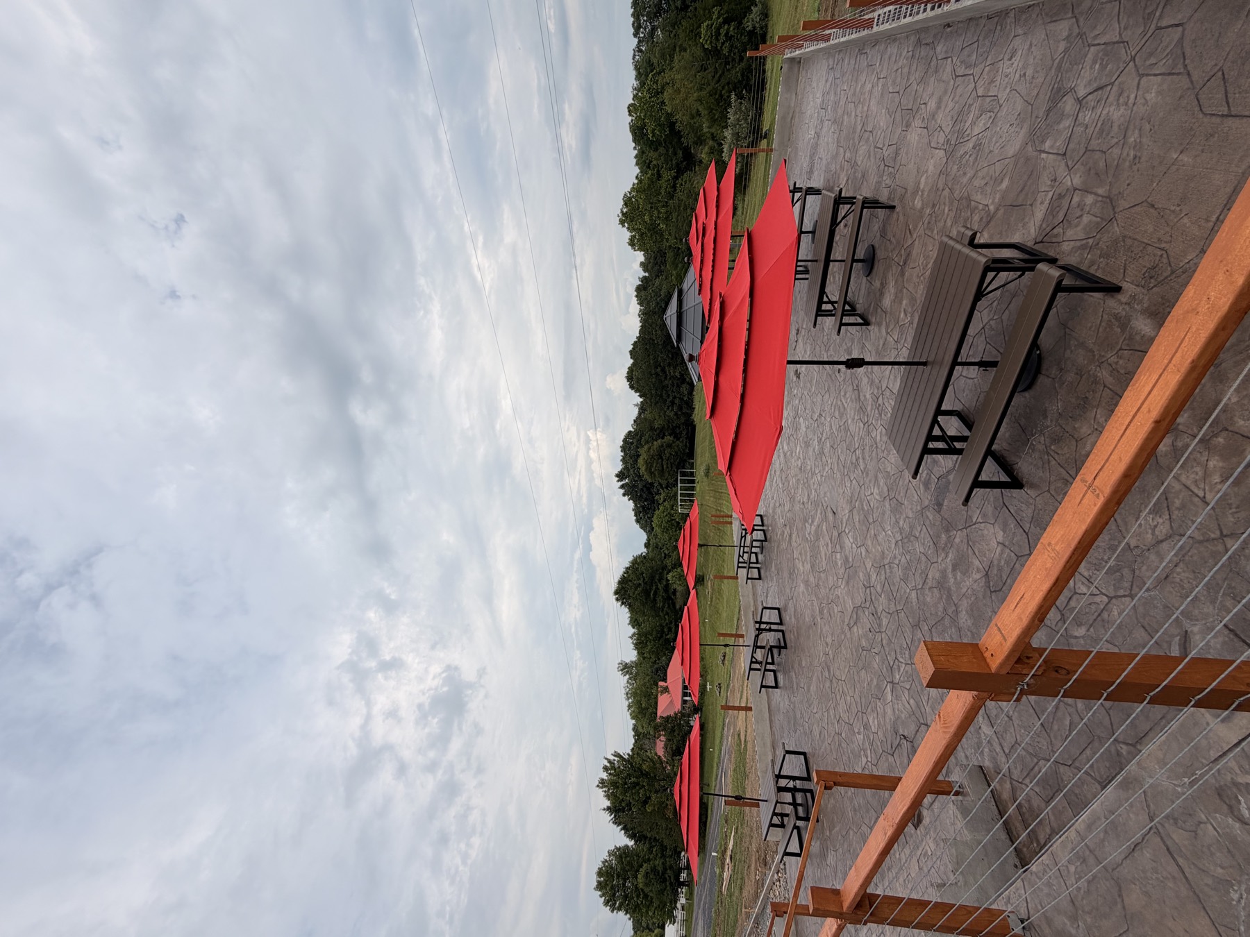 The stamped-concrete lower patio with red umbrellas and picnic tables